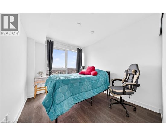 A bedroom with a bed, chair, and window.