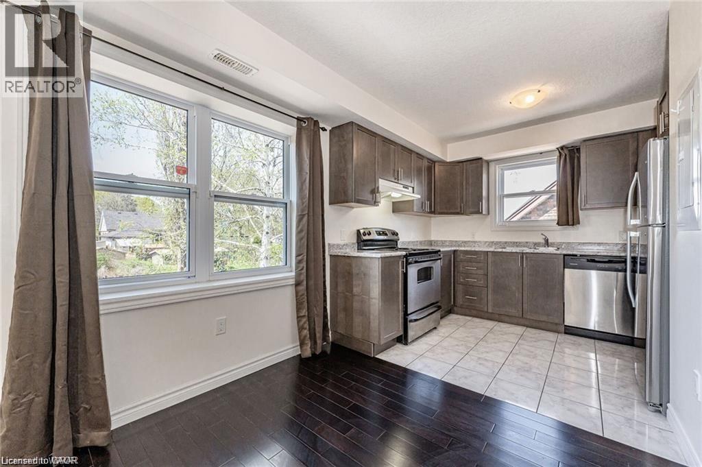 A kitchen with a refrigerator, oven, and sink.