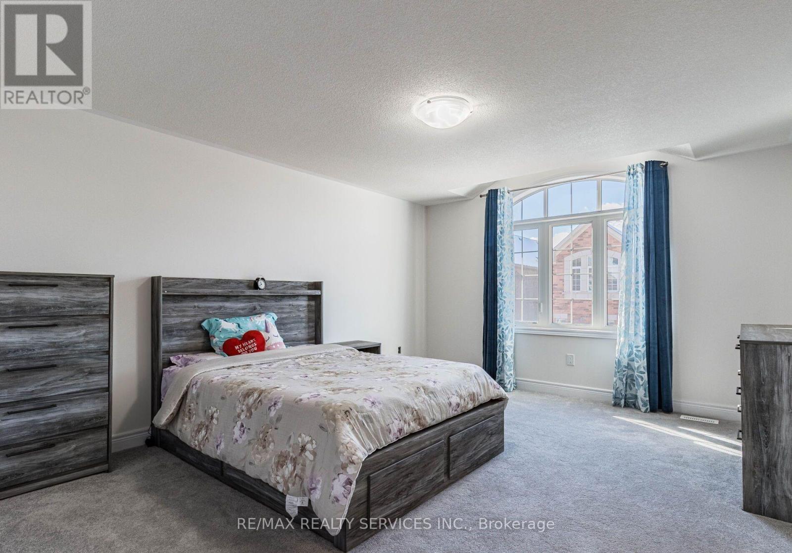 A bedroom with a large bed and a window with curtains.