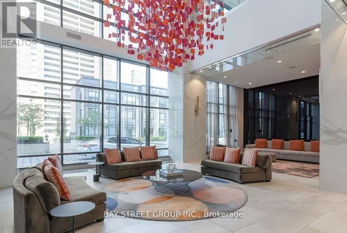 A large, modern living room with a glass wall and a chandelier.