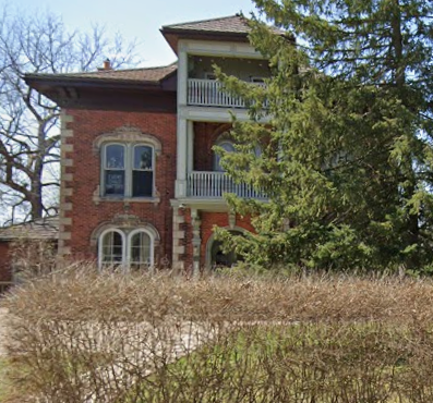 A red brick house with a white balcony.