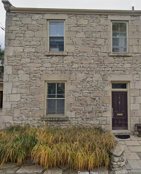 A stone building with a brown door and windows.