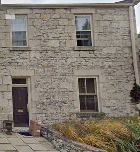 A stone house with a brown door and two windows.