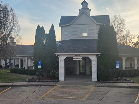 A building with a sign that says "Clubhouse" is in front of some trees.