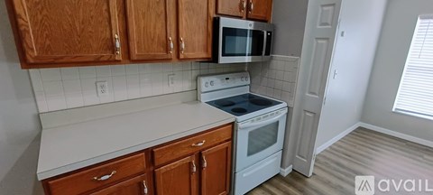 A kitchen with wooden cabinets and a white stove top oven.