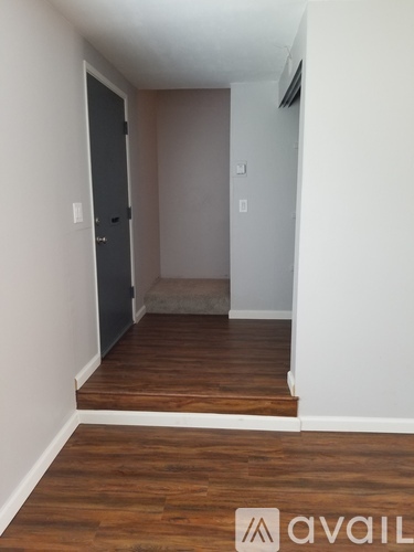 A room with a dark door and wooden floors.