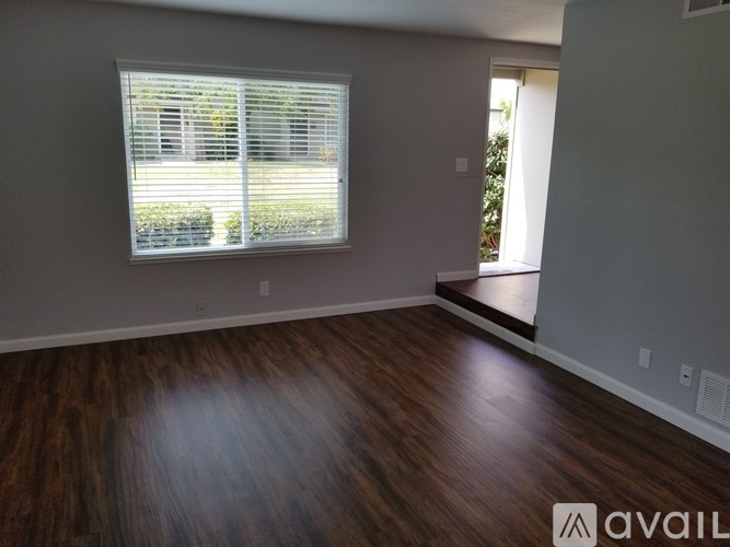 A room with wooden flooring and a window with blinds.