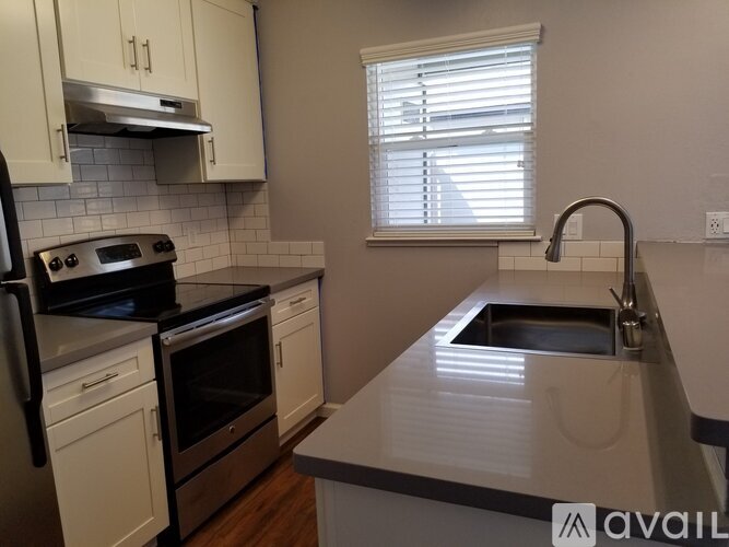 A kitchen with white cabinets and a stainless steel sink.