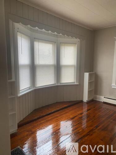 A room with wooden floors and a window with blinds.