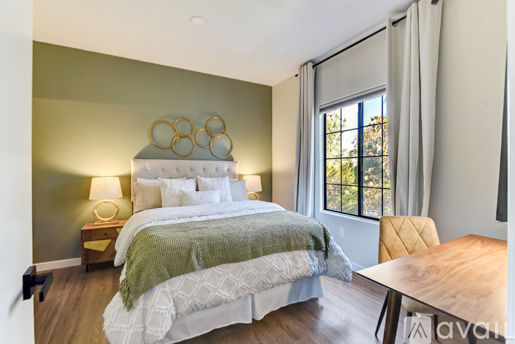 A bedroom with a large bed and a window with curtains.