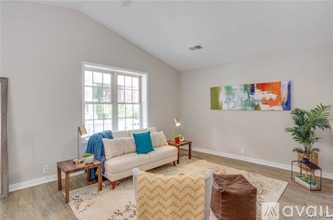 A living room with a couch, a coffee table, a rug, and a painting on the wall.