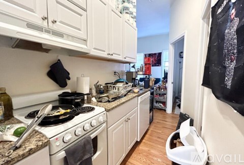 A kitchen with a stove top oven and white cabinets.