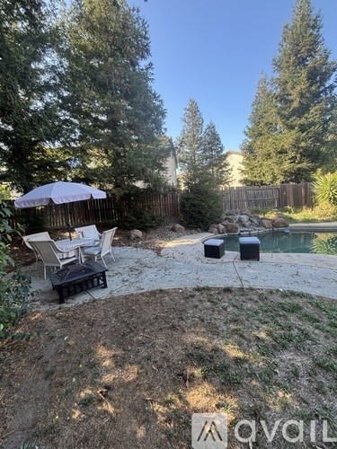 A backyard with a pool and patio furniture.