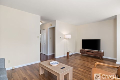 A living room with a wooden floor and a television on a stand.