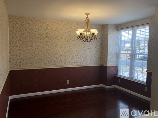 A room with a chandelier and a window with blinds.