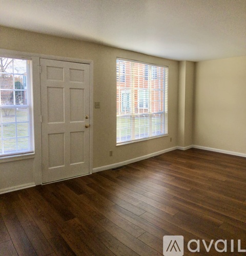 A room with wooden floors and a door leading to a balcony.