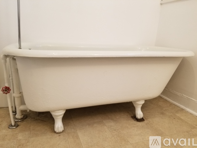 A white claw foot tub with a silver pipe running along the side.