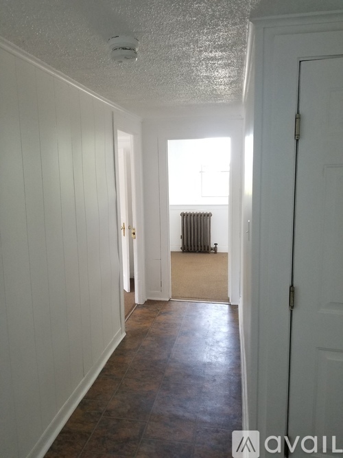 A long hallway with a white door on the right.