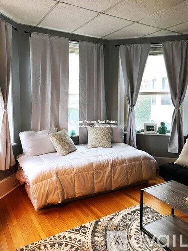 A bedroom with a bed, pillows, and a rug.