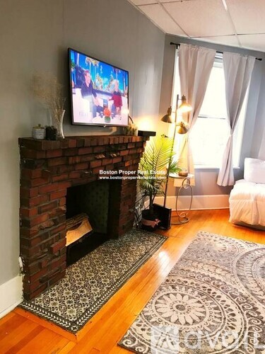 A living room with a fireplace and a television on the wall.