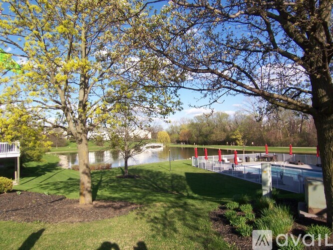 A park with a lake, trees, and a bridge.