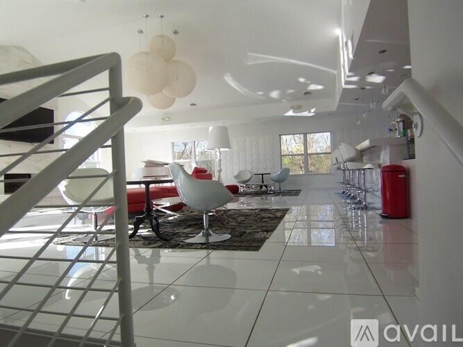 A spacious, white-walled room with a staircase on the left and a red object on the right.
