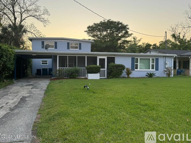 A house with a blue and white exterior is shown with a grassy front yard and a sidewalk leading to the front door.