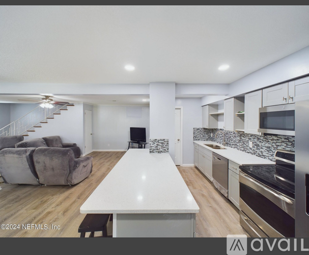 A modern kitchen with a long white table and a grey couch.