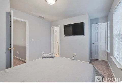 A bedroom with a bed, a television, and a window with blinds.