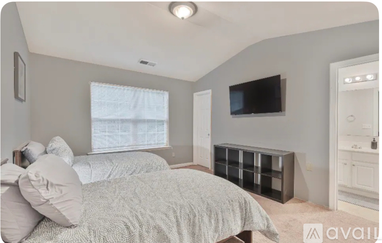 A bedroom with a bed, a television, and a window.