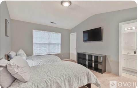 A bedroom with a bed, a television, and a window.
