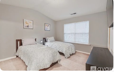 A bedroom with two beds and a window.