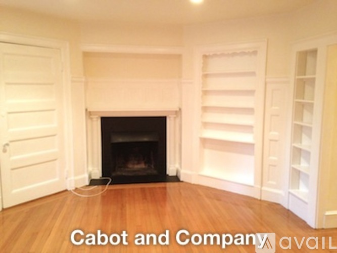 A white room with a fireplace and wooden floors.