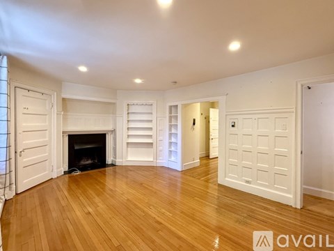 A white room with a fireplace and wooden floors.