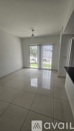 A spacious room with a tiled floor and a sliding glass door leading to a garden.