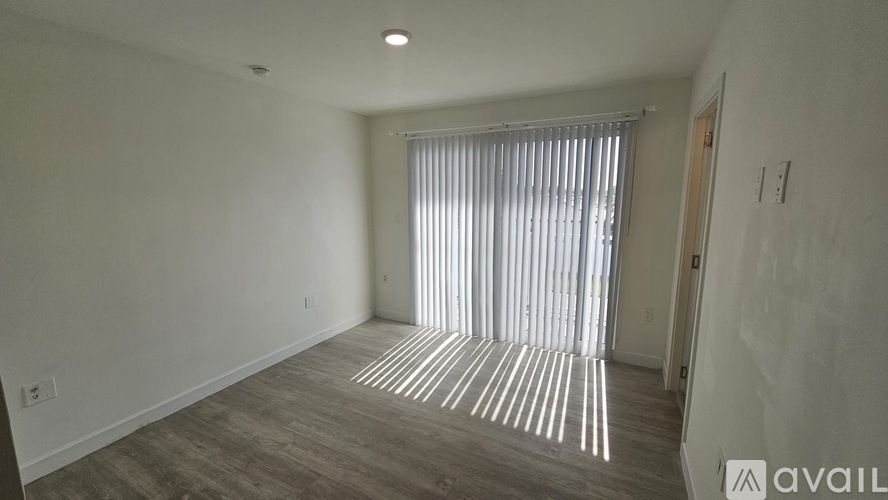 A room with a large window covered by vertical blinds.
