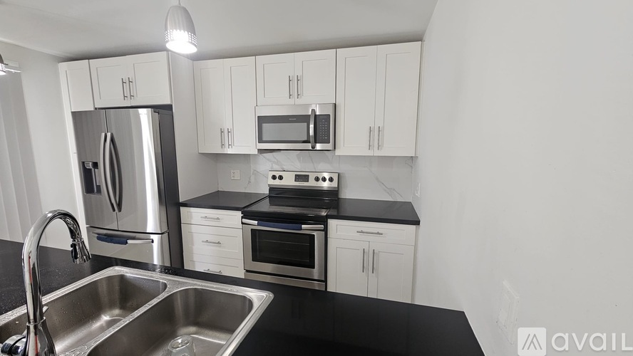 A kitchen with white cabinets and a stainless steel refrigerator.