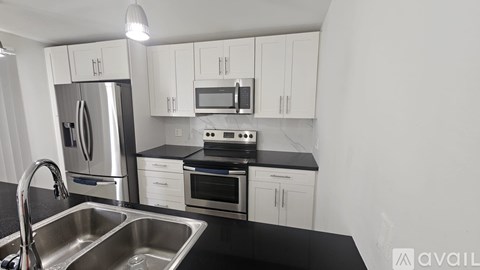 A kitchen with white cabinets and a stainless steel refrigerator.