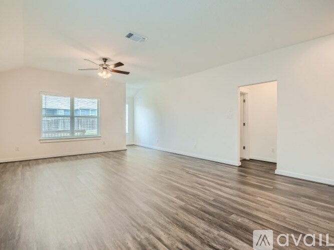 A spacious room with a ceiling fan and wooden flooring.