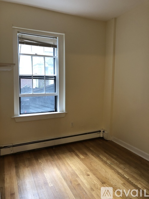 A room with a window and wooden flooring.
