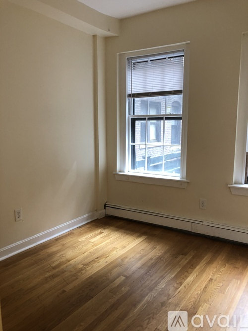 A room with wooden floors and a window showing a building outside.
