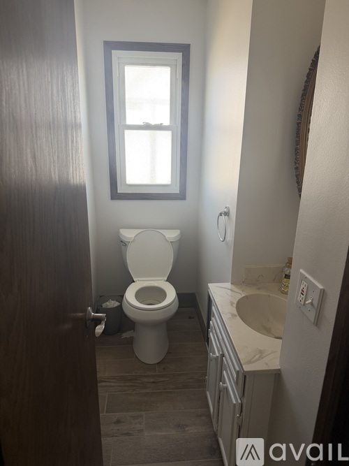 A bathroom with a toilet, sink, and window.