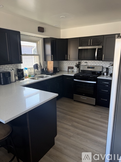 A kitchen with black cabinets and a white countertop.