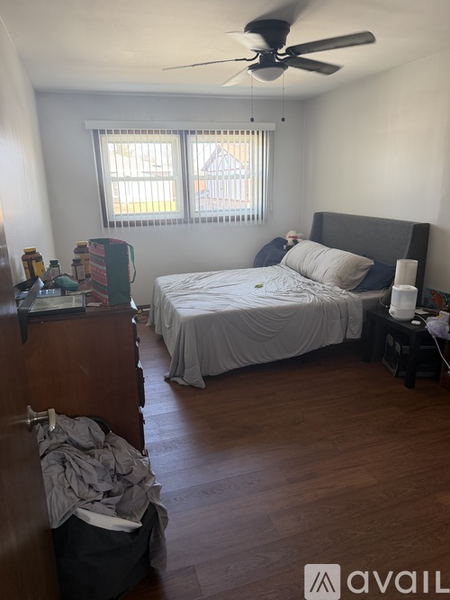 A bedroom with a bed, dresser, and window with blinds.