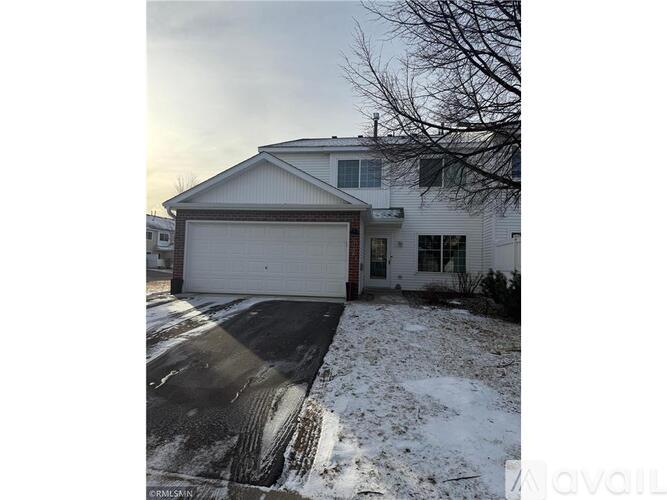 A house with a white garage door and a driveway covered in snow.