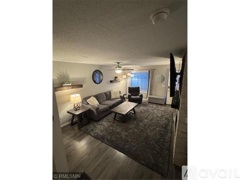 A living room with a grey couch and a clock on the wall.
