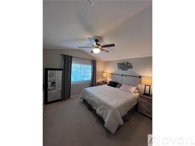 A bedroom with a bed, nightstand, and ceiling fan.