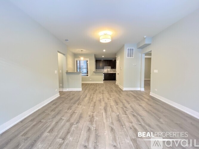 A spacious room with wooden flooring and a large window.