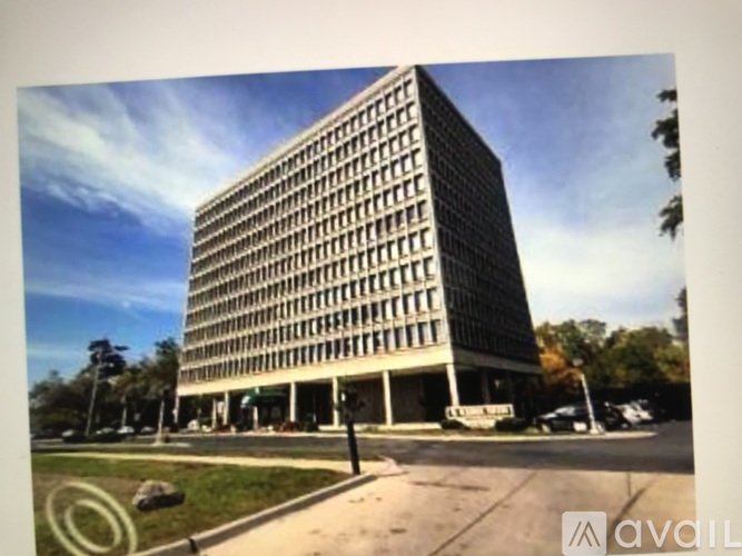 A tall building with many windows is surrounded by a grassy area.