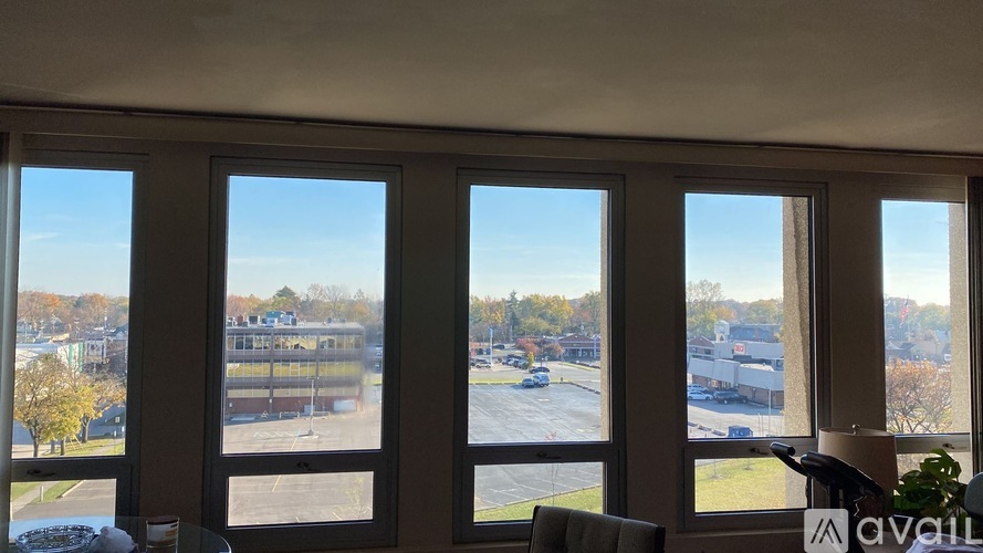 A room with large windows overlooking a parking lot and buildings.